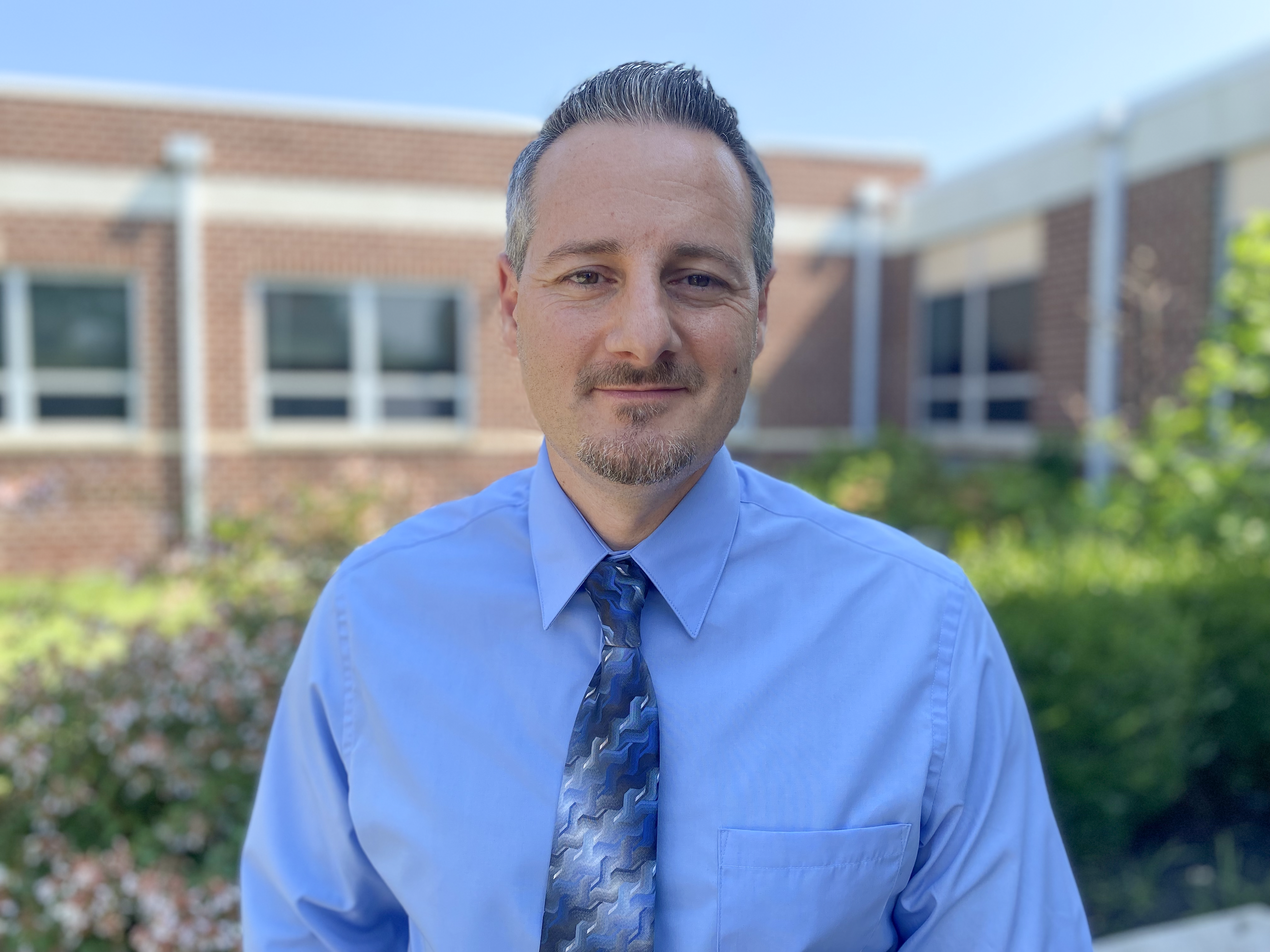 Principal Christian Paskalides posing for a photo outside of the school.